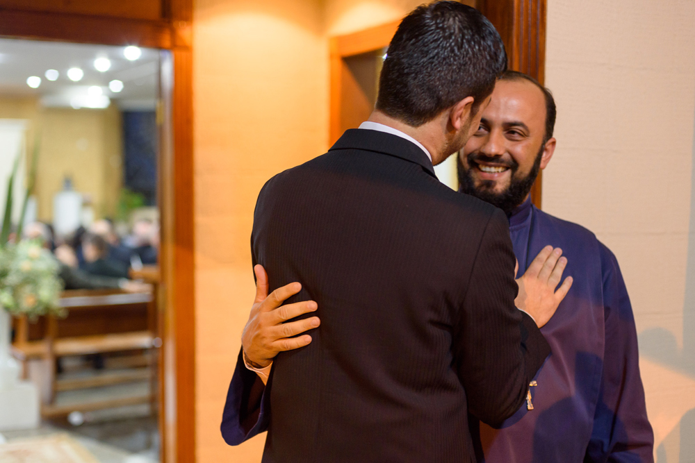 Noivo cumprimentando o padre na frente da igreja, amigos de longa data