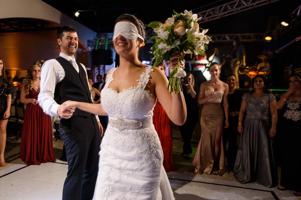 Hora do bouquet. A noiva vendada roda para entregar para uma das meninas solteiras