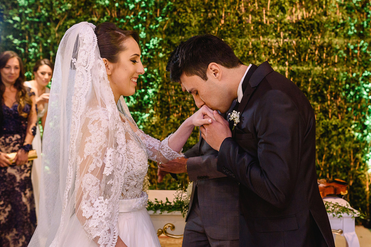 Noivo beija a aliança da noiva