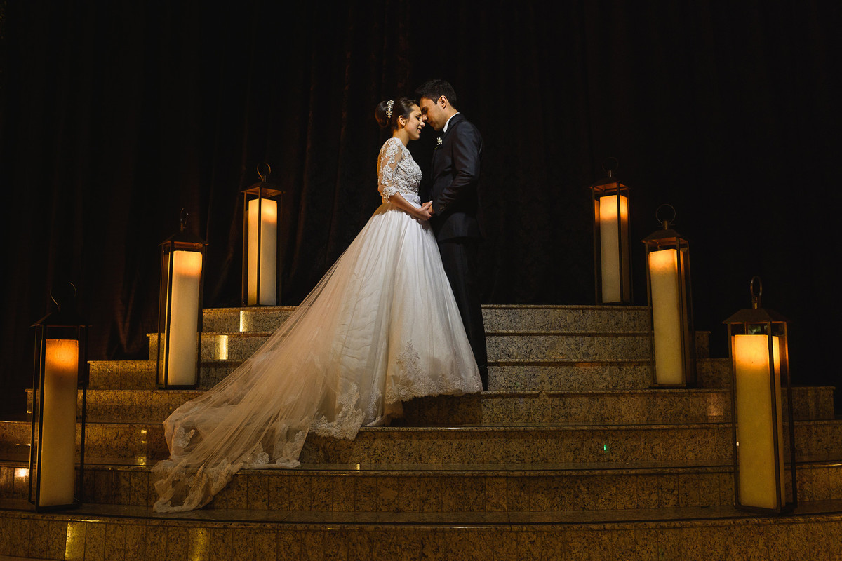 Foto dos noivos na escadaria em meio as velas