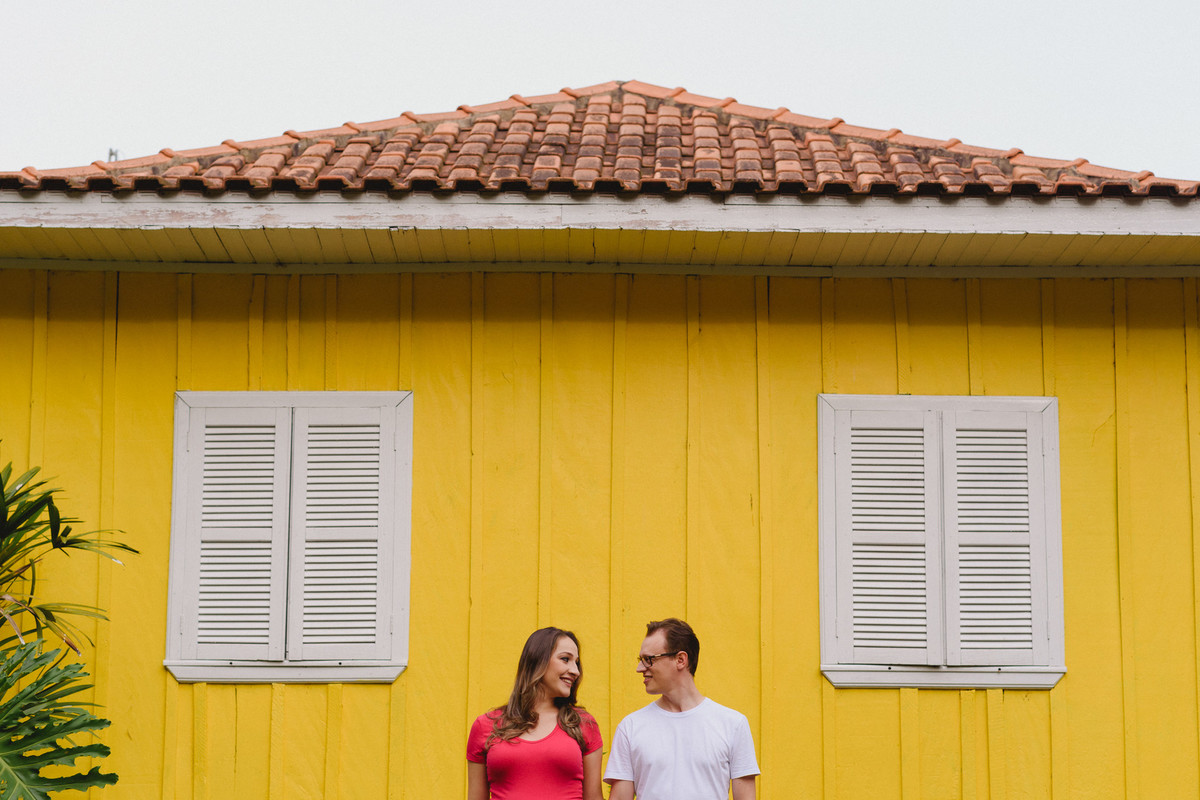 Casal se olhando em frente a parede amarela, entre duas janelas