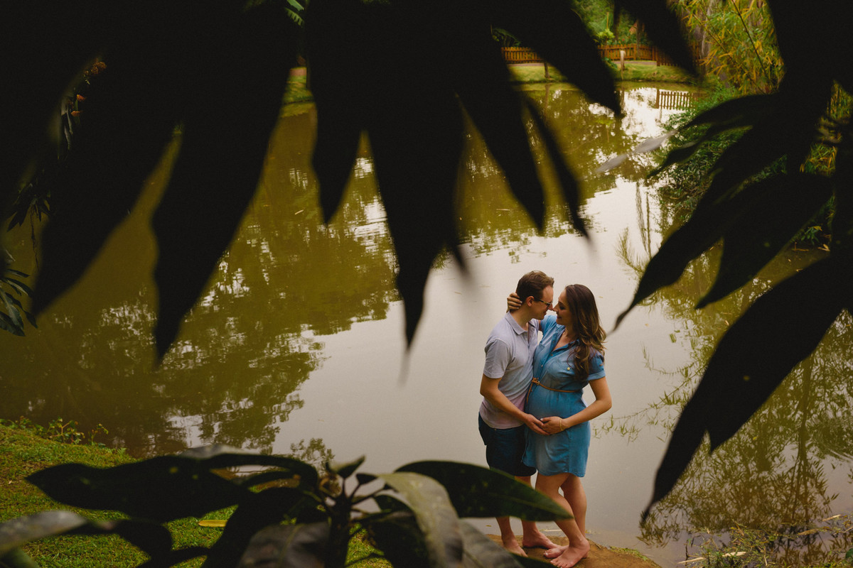 O casal perto do lago por entre as folhas da árvore