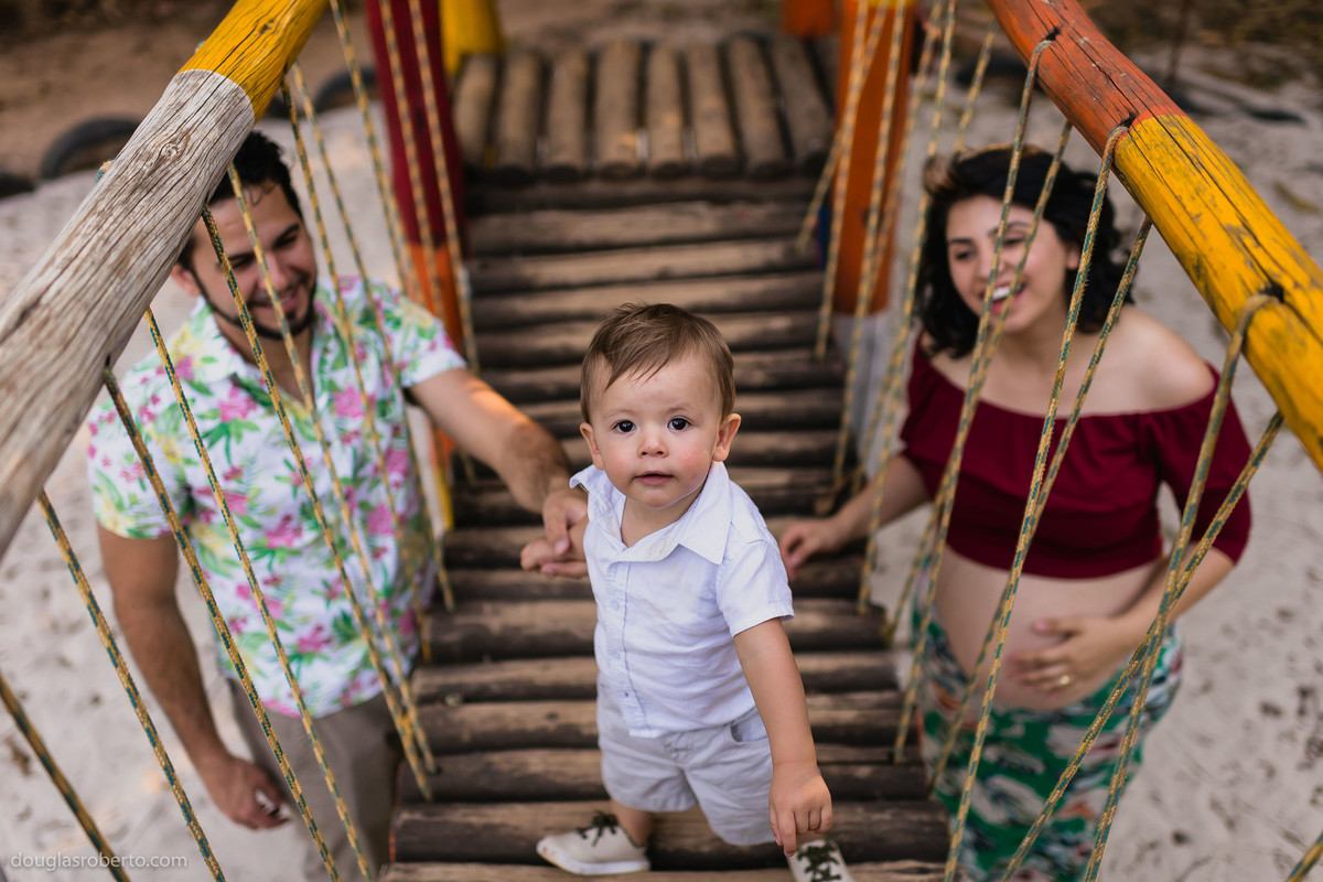 criança brincando no parquinho com os pais