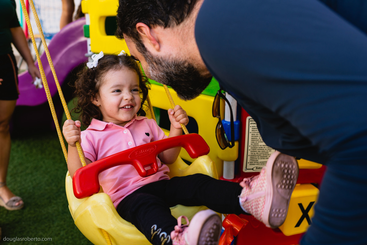 pai brincando com a filha no balanço