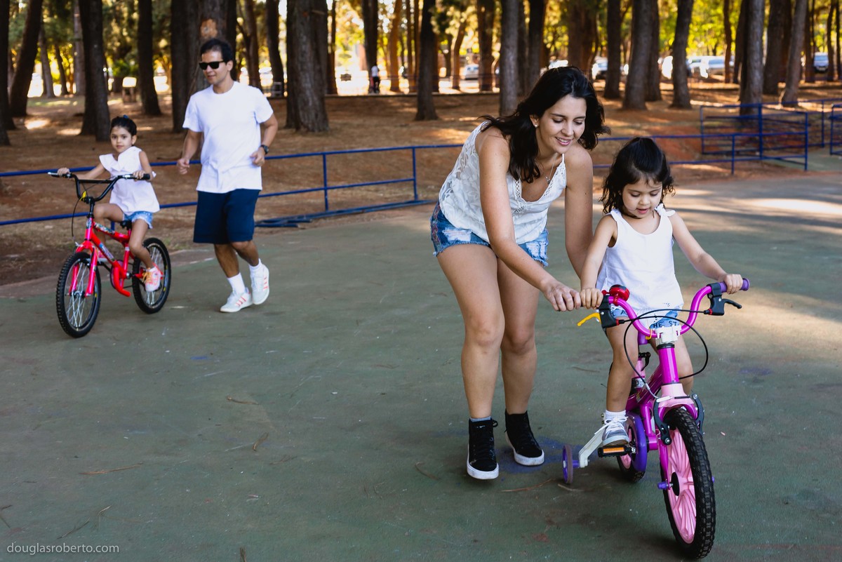 pais ensinando filhas a andarem de bike