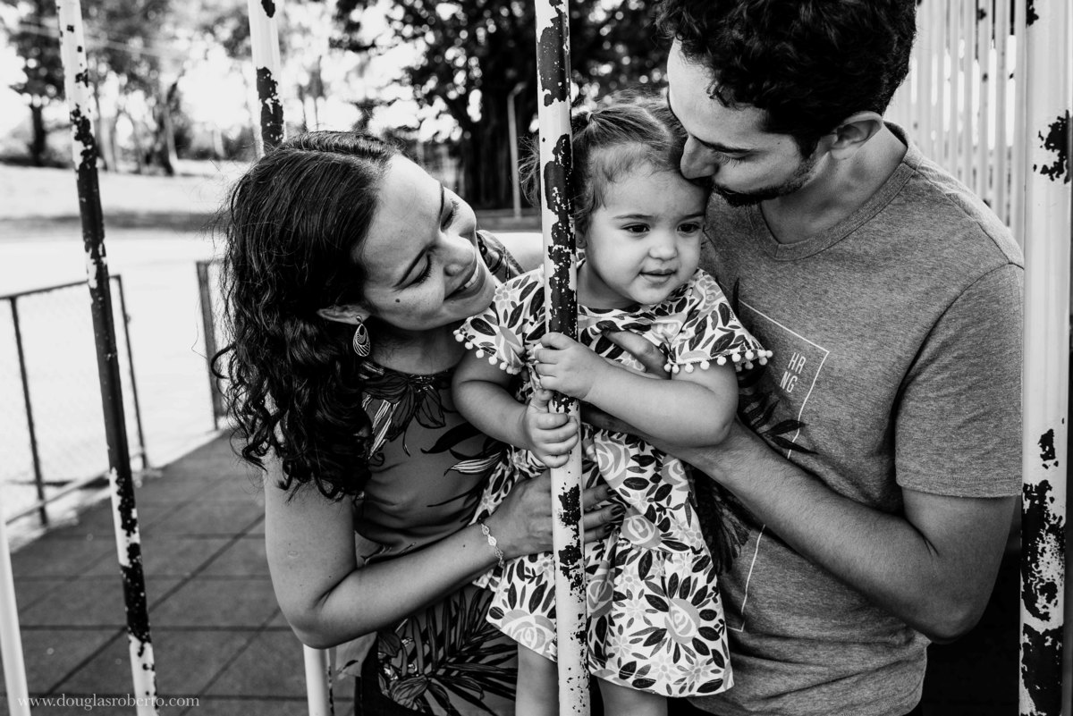 pais abraçando e brincando com a filha