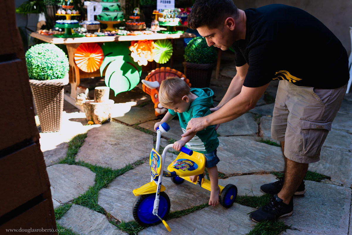 pai ensinando filho a andar de triciclo