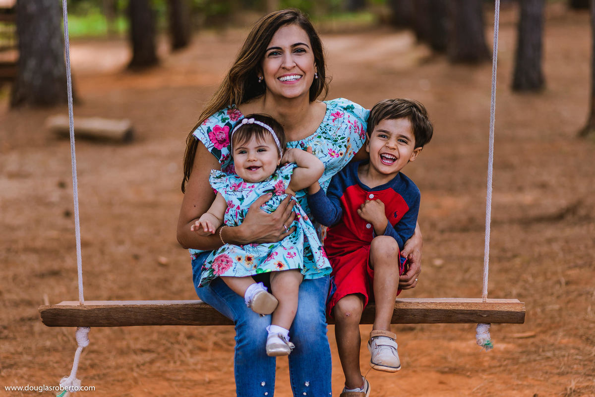 mãe binando com filhos no balanço