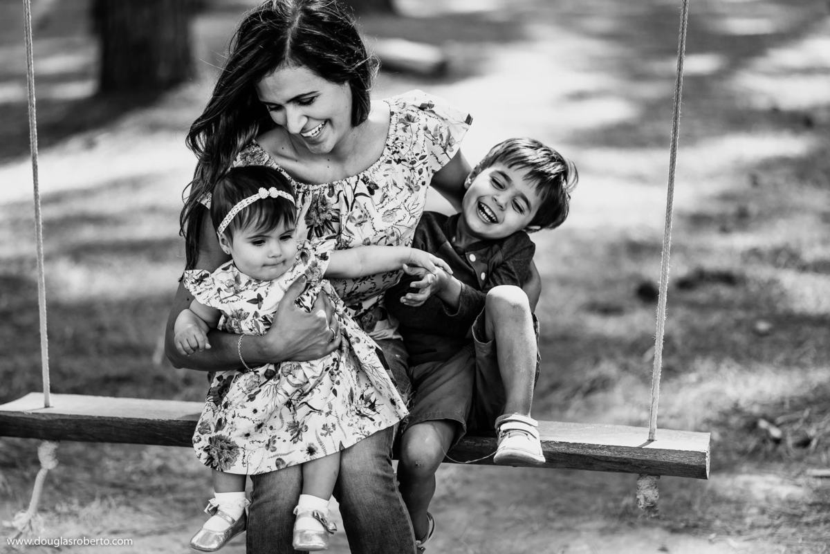 mãe binando com filhos no balanço