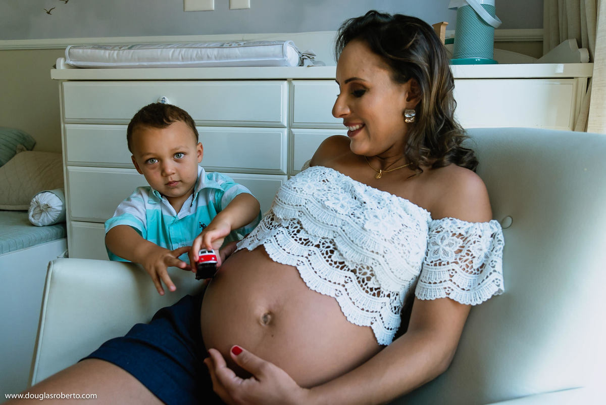 filho brincando com a barrida da mãe que está gravida