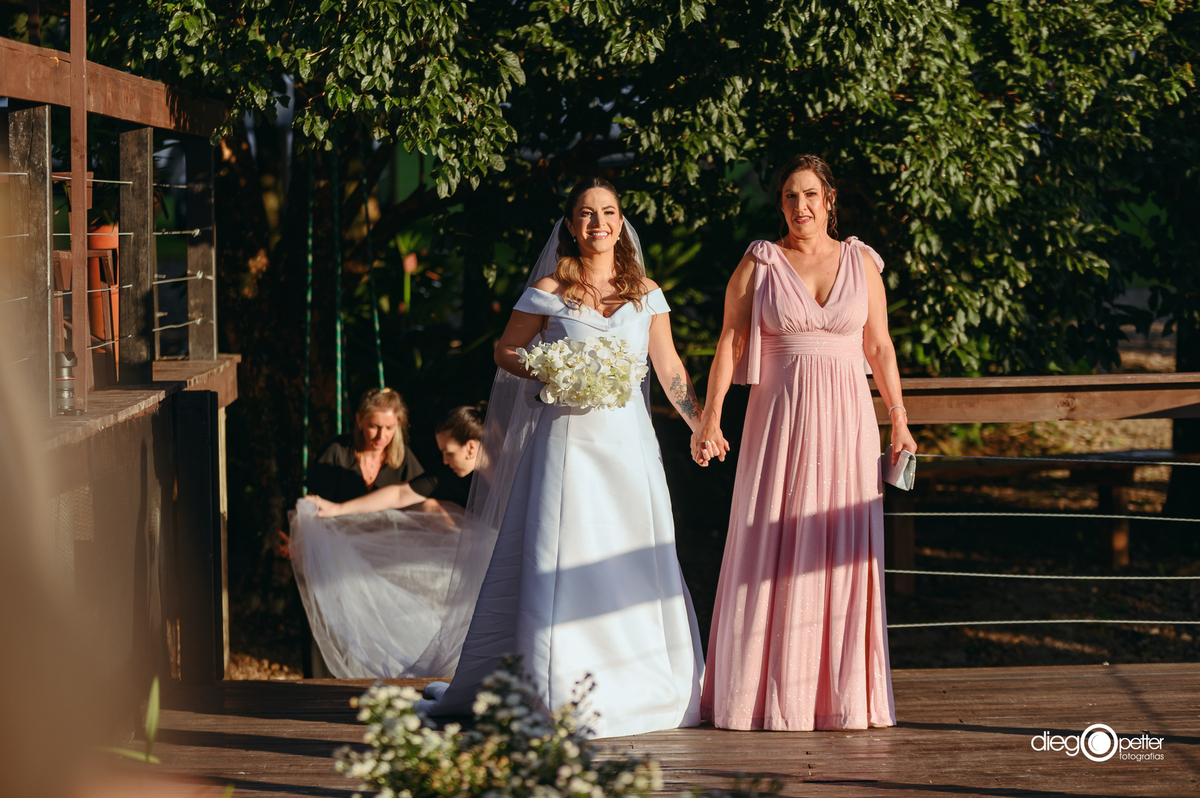 noivo entrando com a mãe no dia do casamento ao ar livre