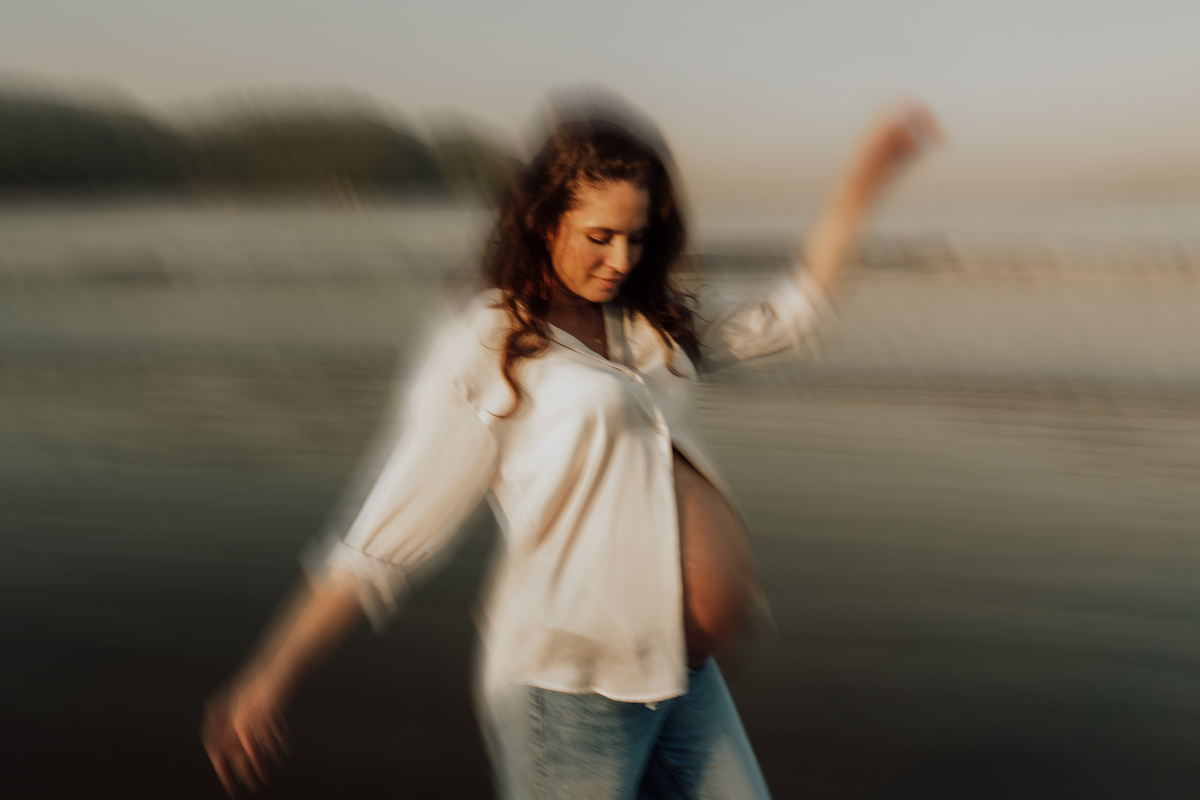 Fotografia de grávida na praia de Santos, usando calça jeans e camisa, capturando a tranquilidade da maternidade com luz natural suave. Foto ideal para ensaios de gestantes que buscam registros emocionantes da gravidez.