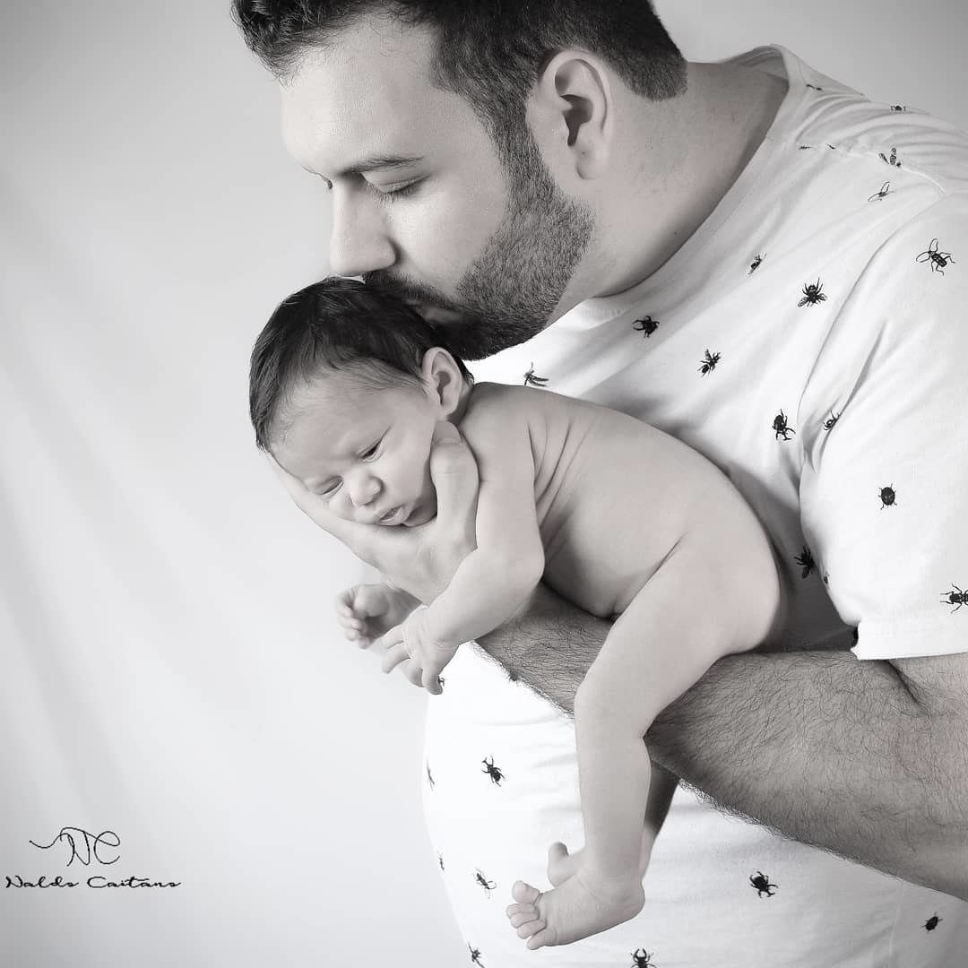 Ensaio newbron fotógrafo foto preto branco o pai esta com o bebê em seu braço beijando fotógrafo Naldo Caitano -Praia Grande/ SP