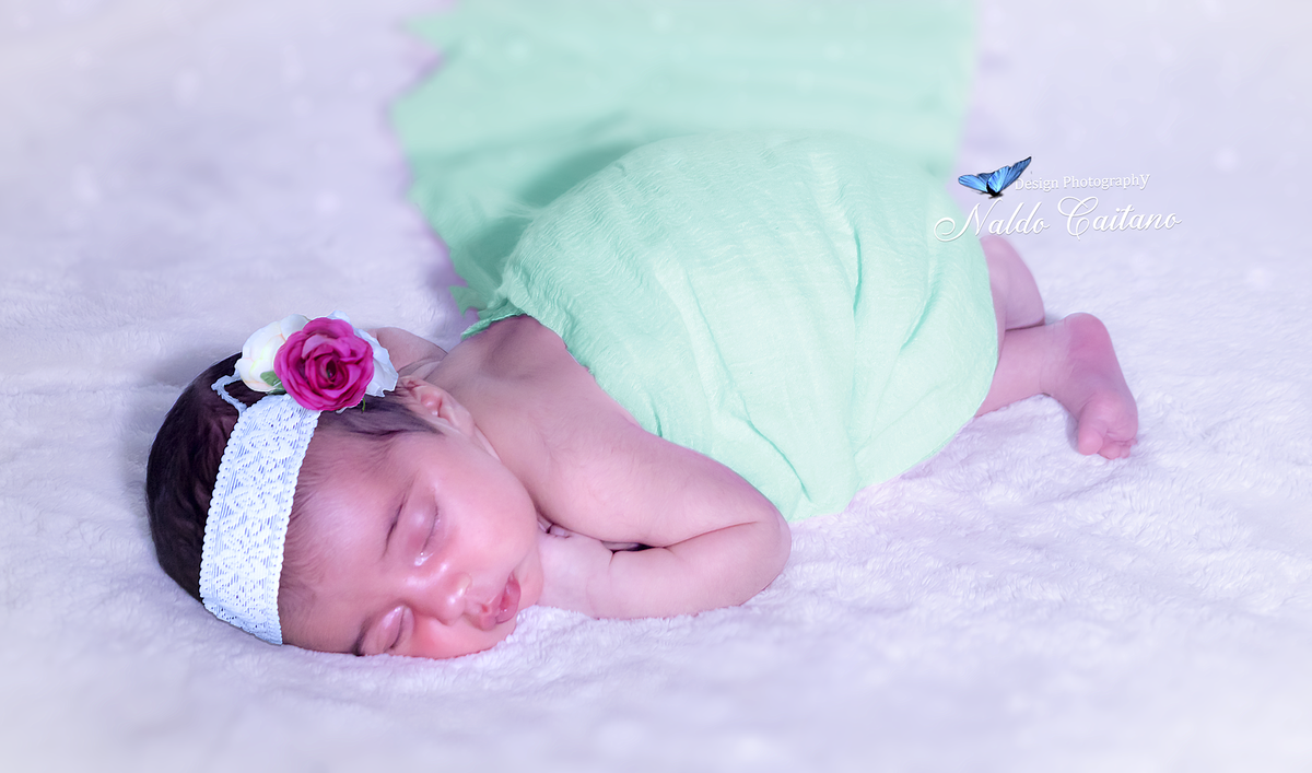 Ensaio fotográfico newbron Laura 13 dias ela esta com figurino lindo  verde e uma acessório branco e roxo no cabelo Santos litoral de São Paulo 