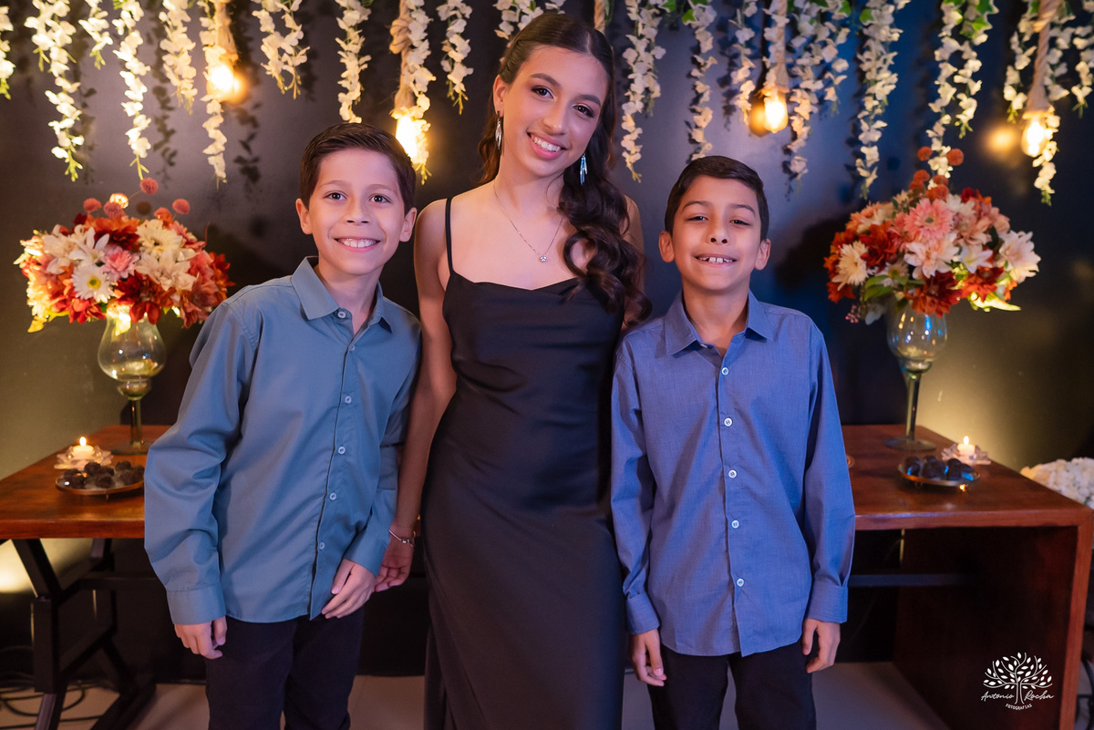 Irmãos ao lado da debutante na festa de 15 anos, fortalecendo laços familiares.