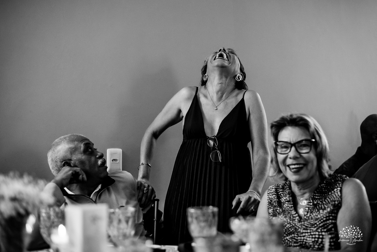 Mãe da debutante sorrindo na mesa com os convidados