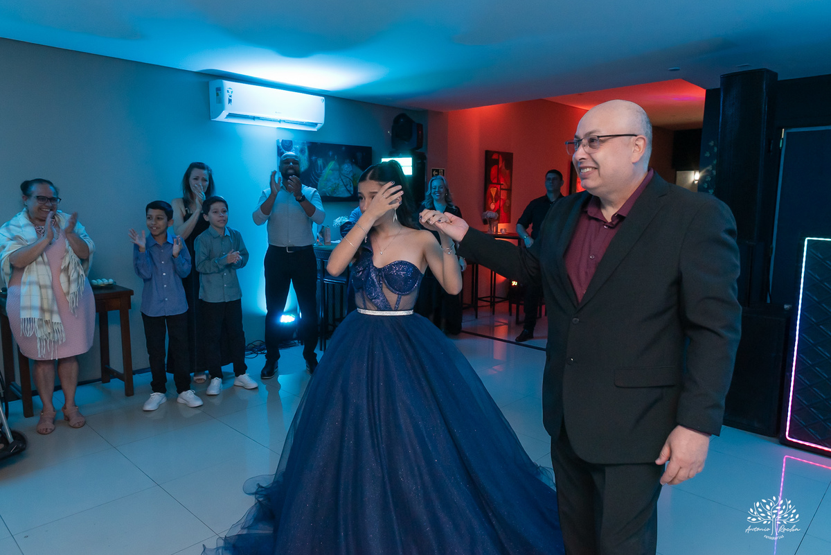 Debutante sendo conduzida pelo pai até o bolo para cantar o parabéns