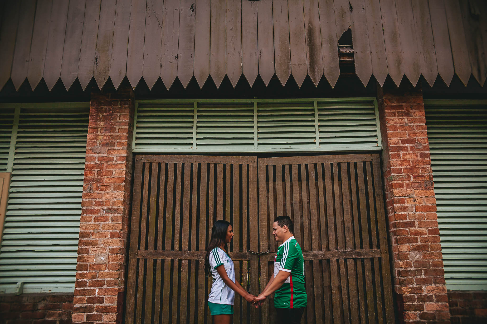 noivos de mãos dadas em frente a portão com uniforme do palmeiras em ensaio pré wedding fotografado por Say Cheese Fotografia