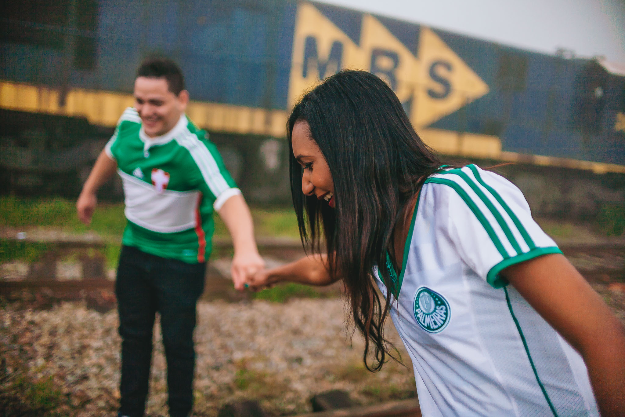 noivos caminhando sobre trilhos de paranapiacaba com uniforme do palmeiras em ensaio pré wedding fotografado por Say Cheese Fotografia