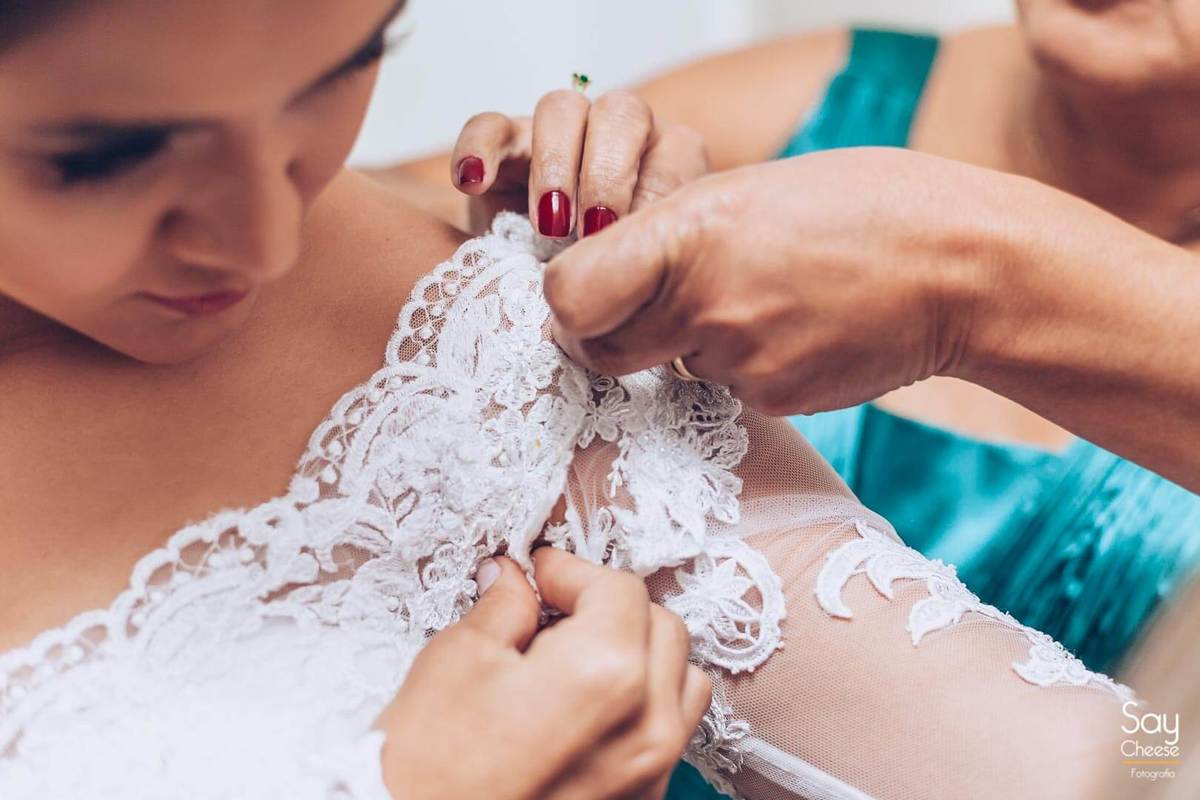 mãe ajudando noiva a colocar o vestido de casamento