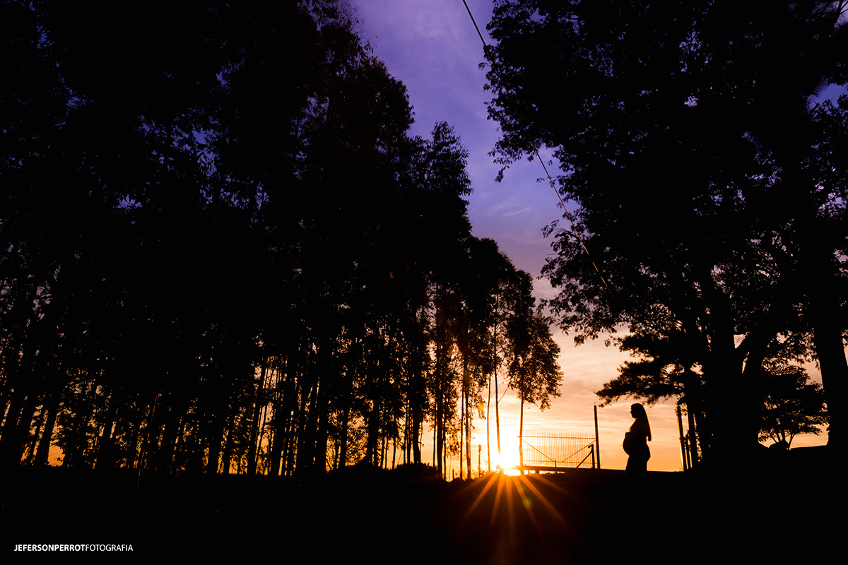 mulher gestante em silhueta em por do sol maringaense
