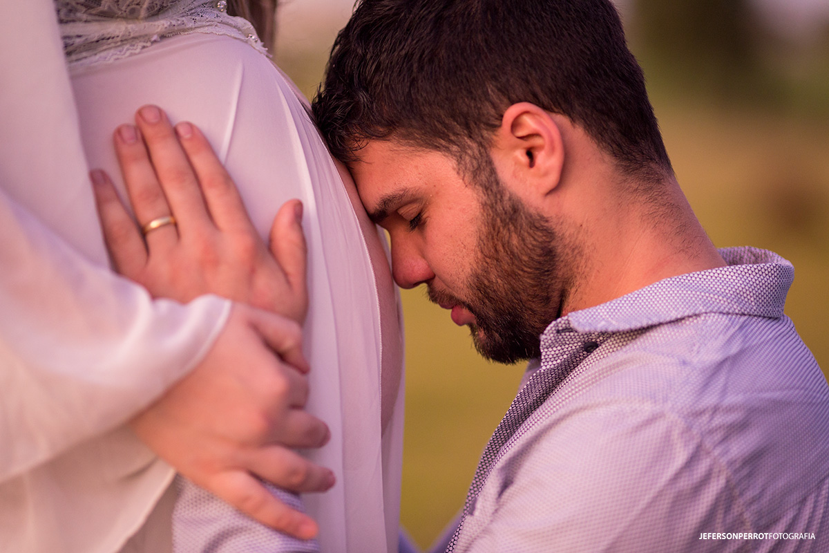 pai ajoelhado sentindo filha na barriga