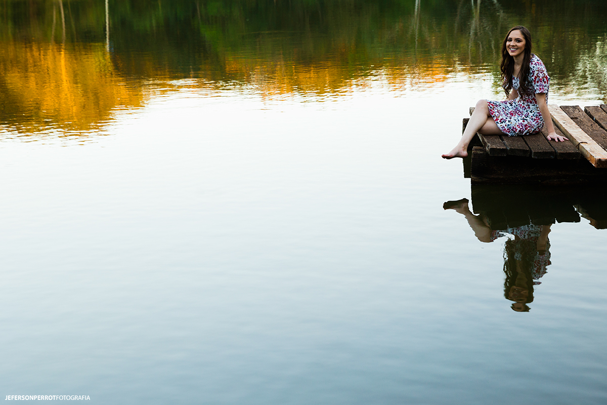 sentada em um pier de um lago no parque