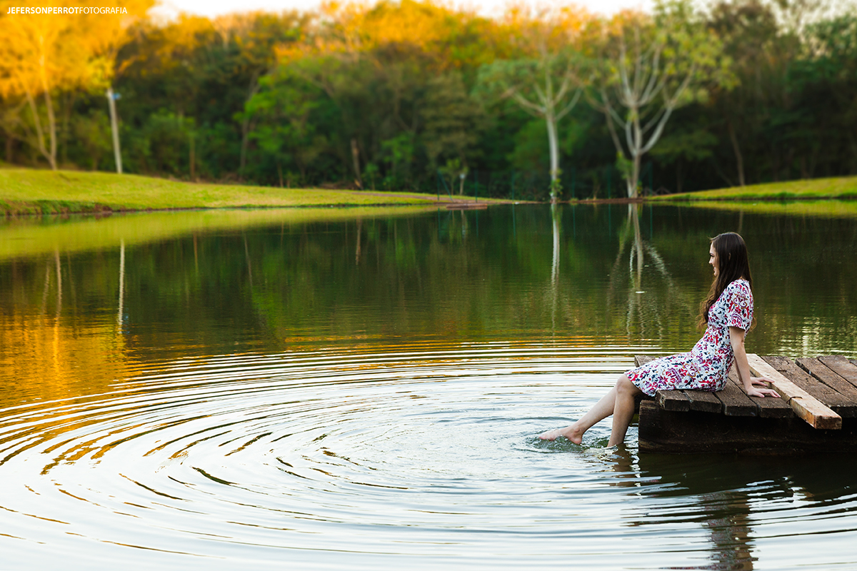 mulher fotografada sentada agitando as águas em um pier