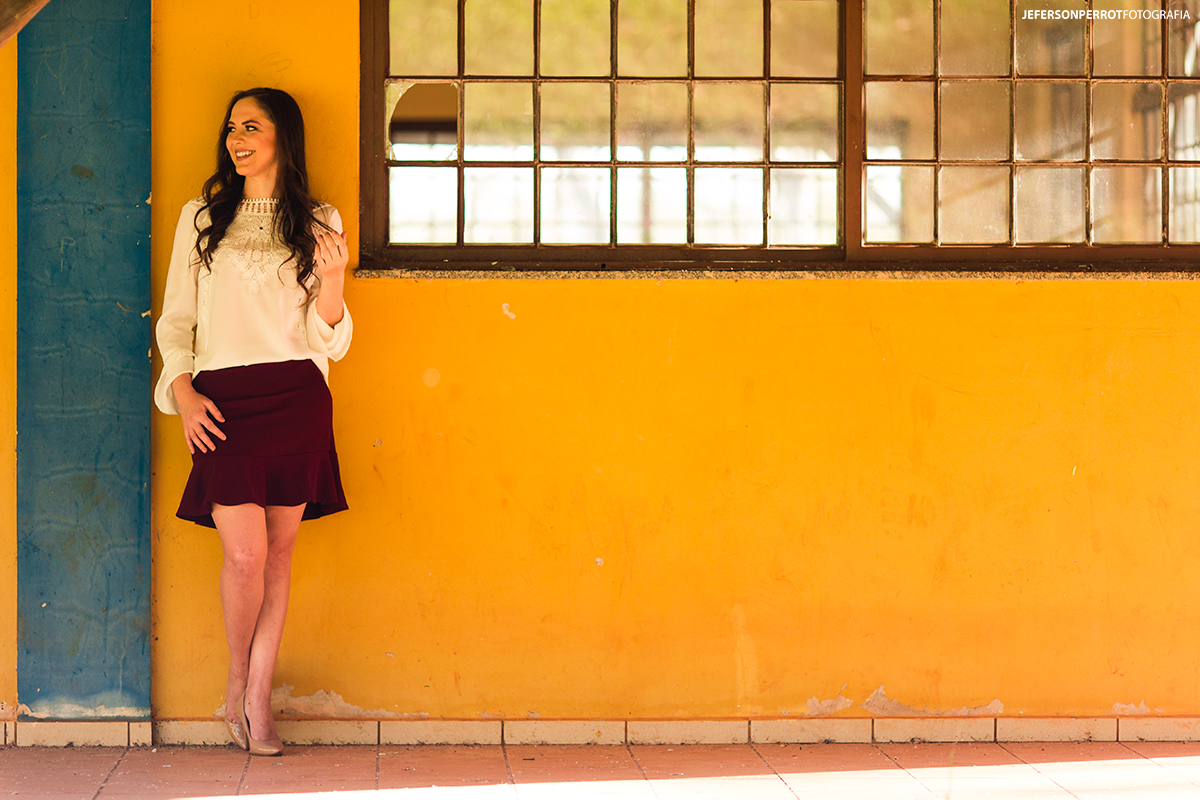 mulher fazendo pose ao ser fotografada em uma parece amarela