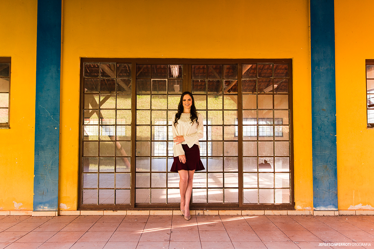 mulher fotografada em uma porta de vidros com paredes amarelas