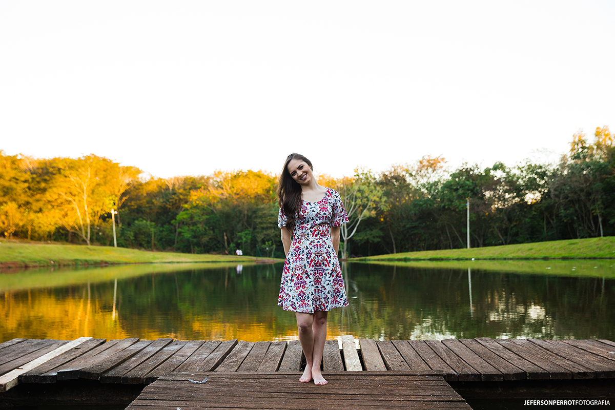 mulher fotografada posando em um pier de um lago