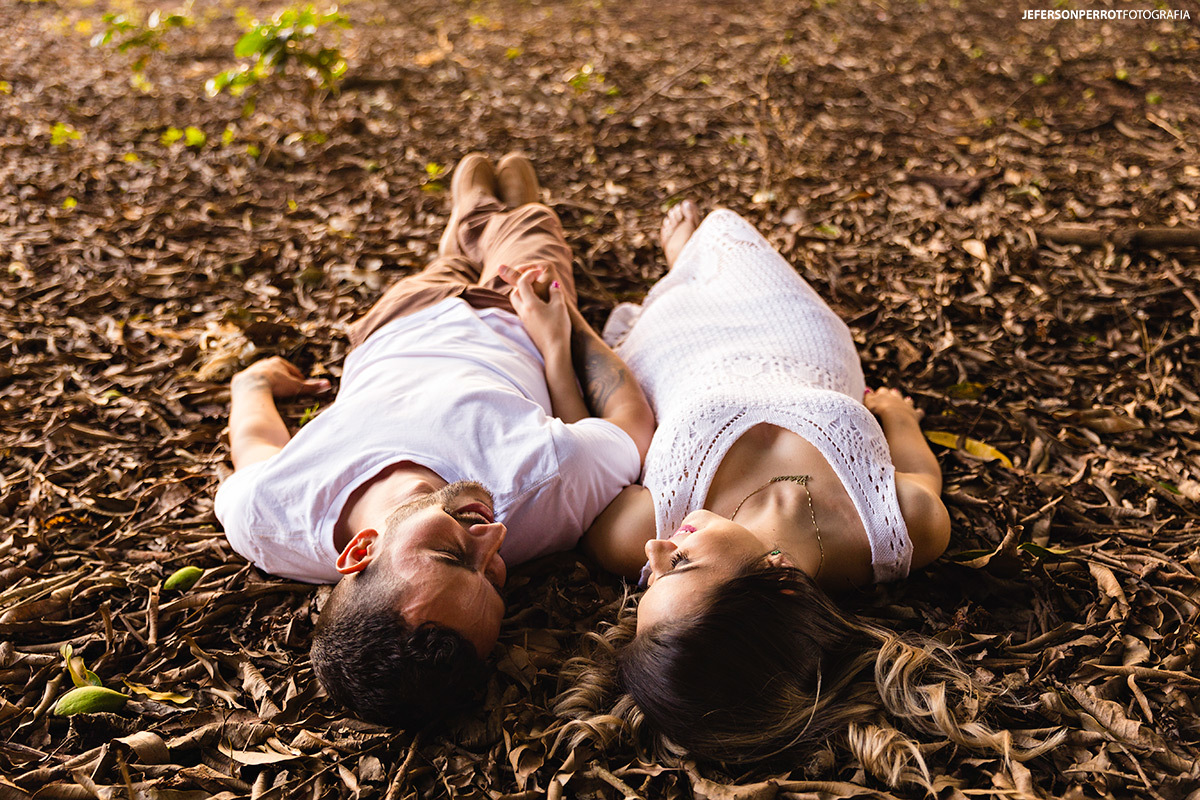 noivos se olhando deitados sobre folhas secas em ensaio pre-wedding