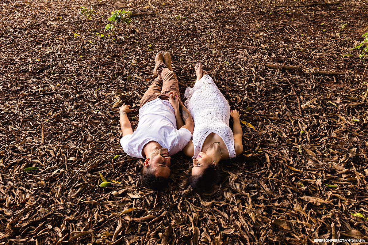 casal de noivos deitados sobre folhas em ensaio fotográfico romântico