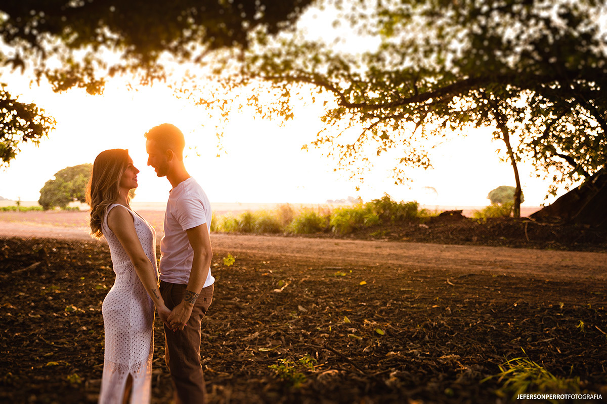 casal se olhando sorridente em por do sol incrível durante ensaio fotográfico pre-wedding 