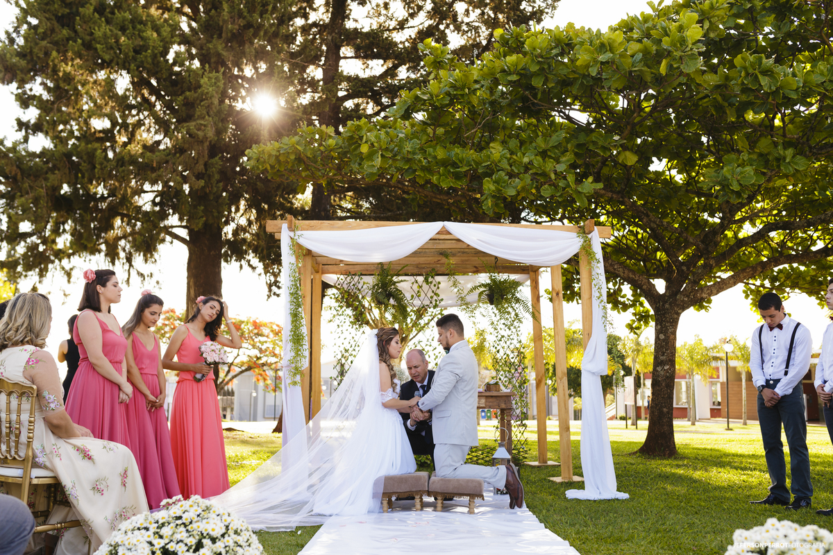 noivos orando ajoelhados em lindo casamento ao ar livre