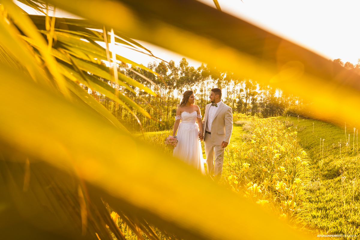 noivos recém-casados caminhando em campo verde com lindo sol dourado