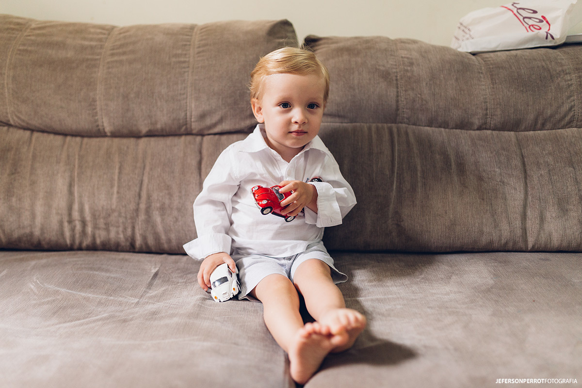 menino loiro brincando no sofá