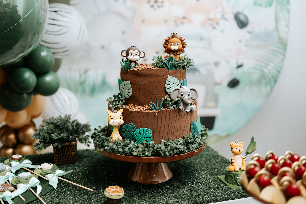 Foto em detalhe do bolo temático de dois andares decorado com animais da selva.