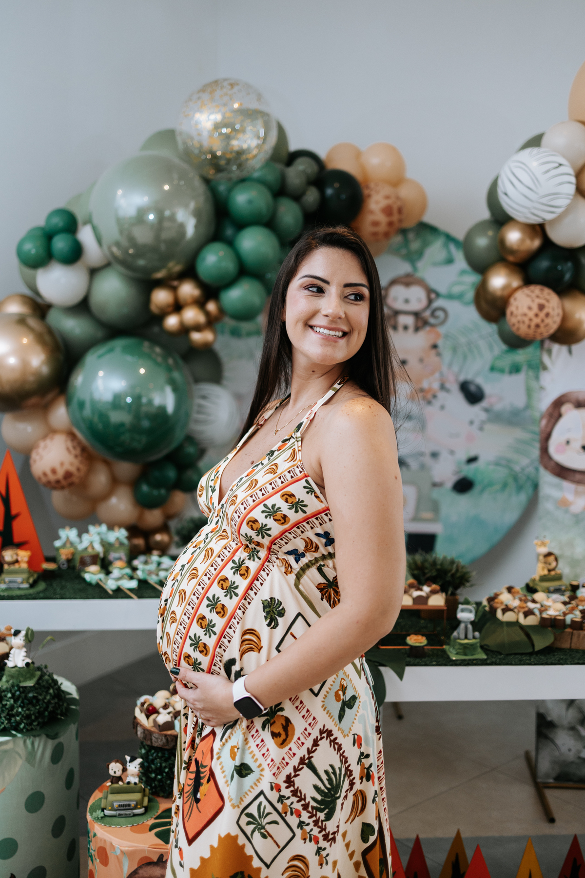 Foto de close da gestante sorridente exibindo a barriga na decoração.