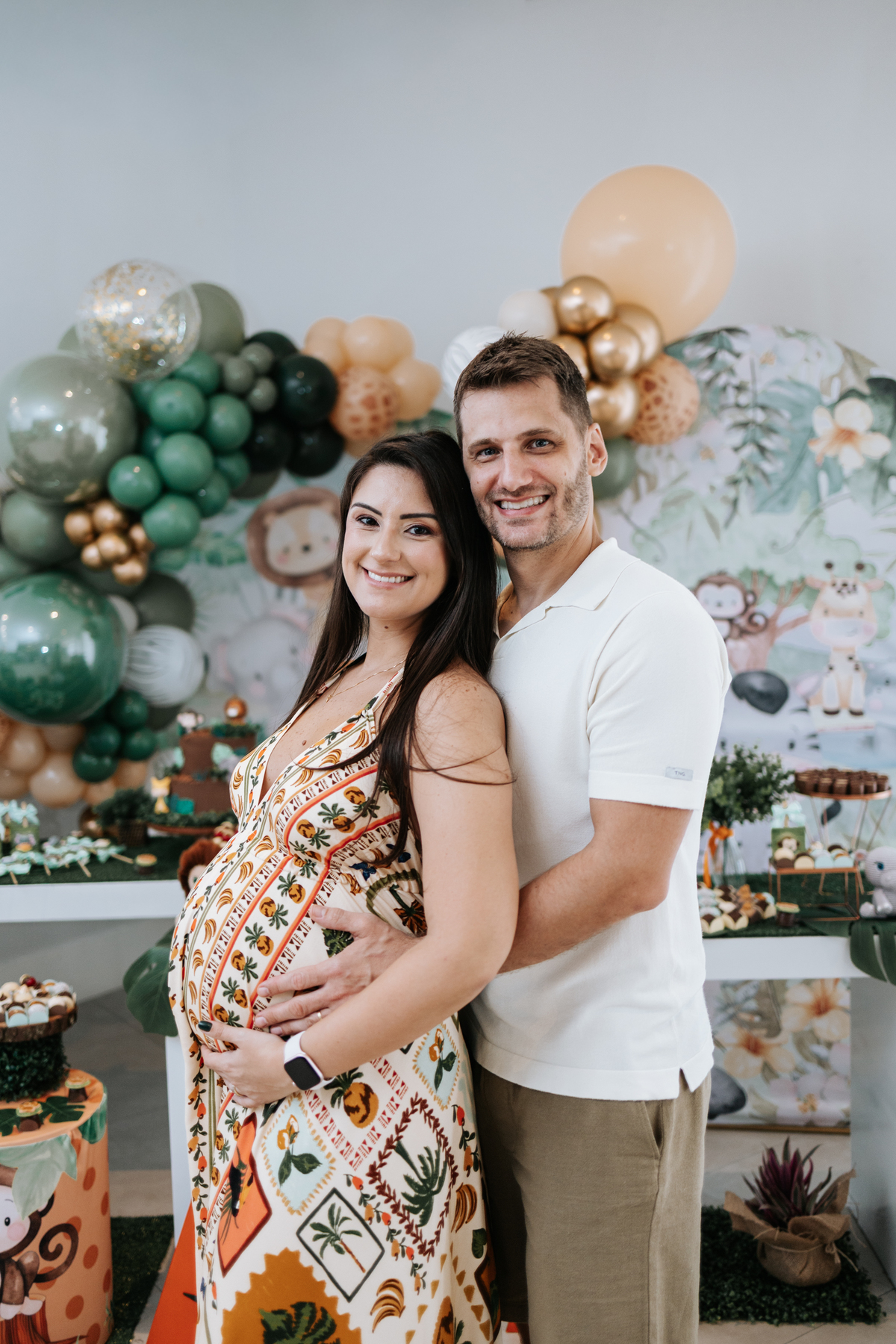 Foto da gestante abraçada pelo parceiro em retrato oficial do evento.