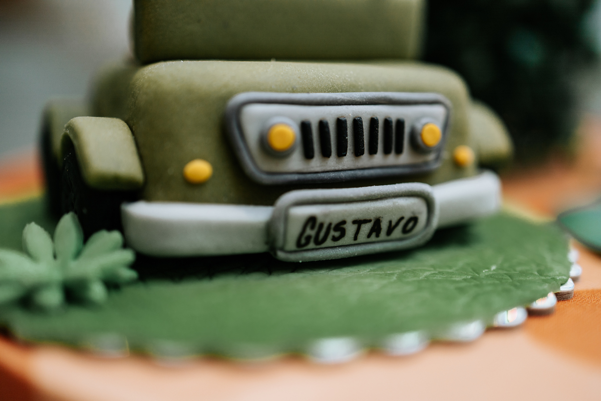 Foto em detalhe de bolo decorado em formato de jipe com o nome 