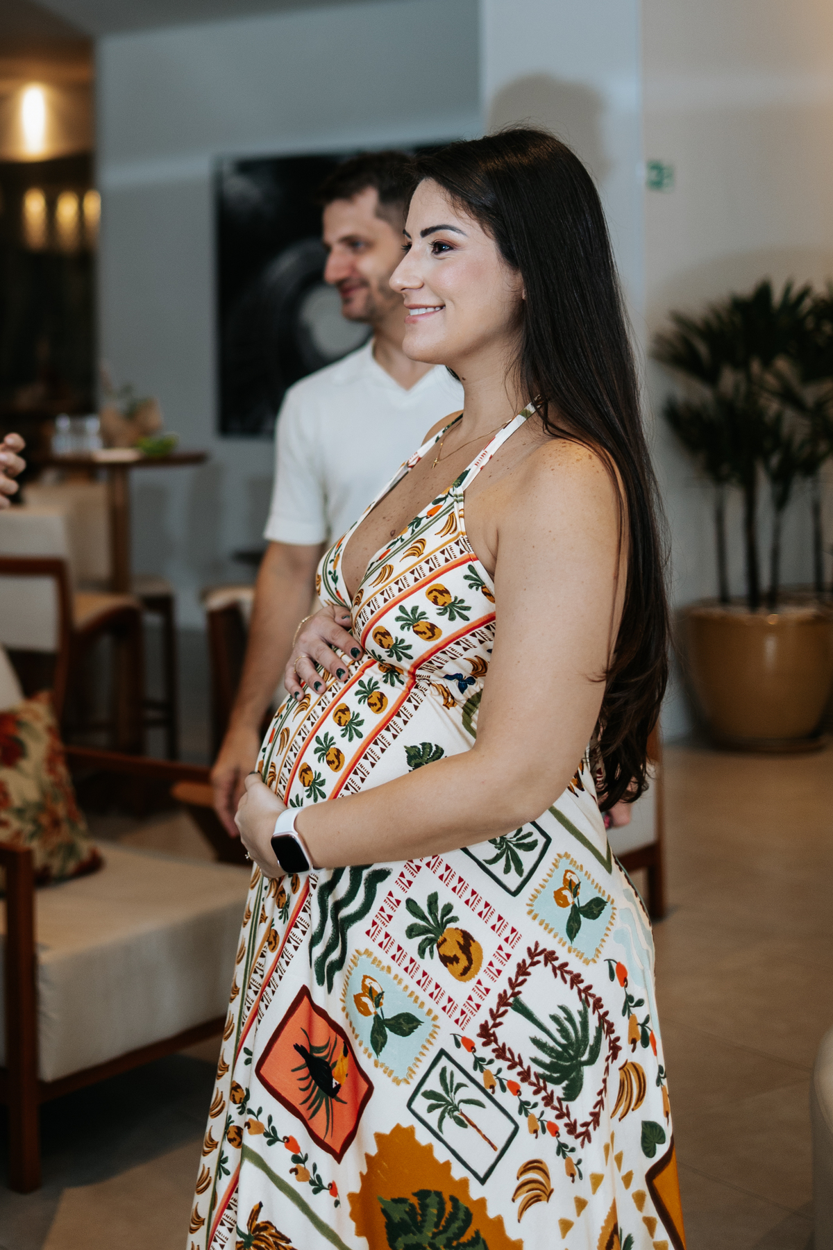 Foto aproximada da gestante com as mãos sobre a barriga na festa.