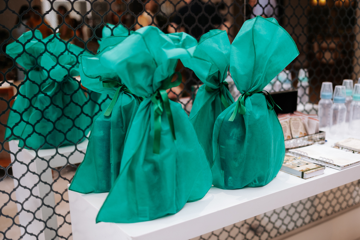 Foto de sacolinhas de lembrancinhas em tecido verde amarradas com laço.