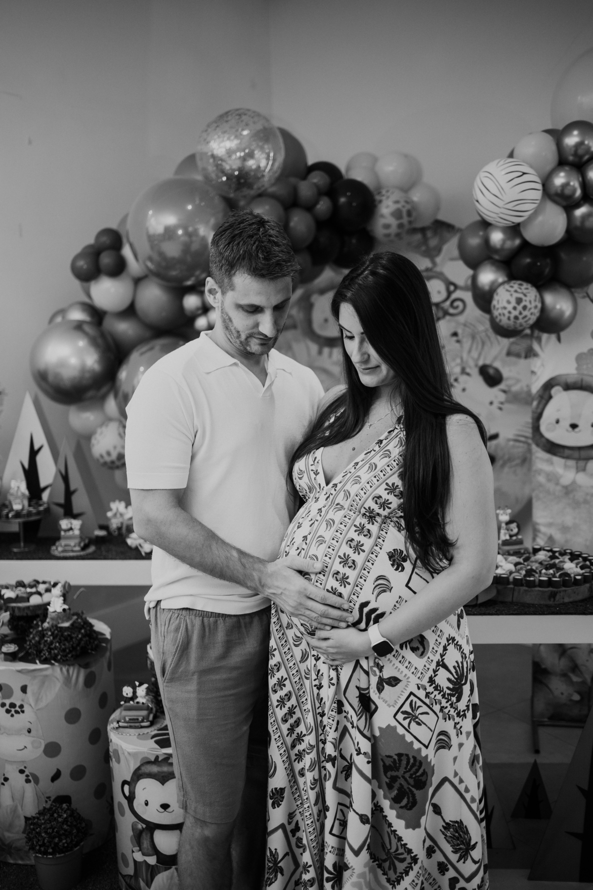 Foto em preto e branco do casal olhando para a barriga da gestante.