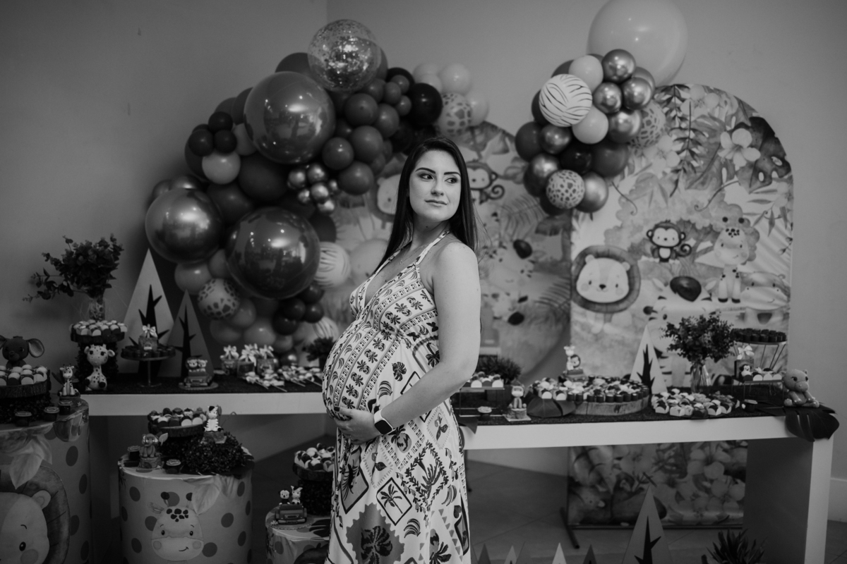 Foto em preto e branco da gestante posando em frente ao painel de balões.