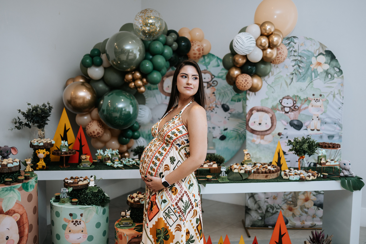 Foto da gestante sorridente no centro da decoração temática.