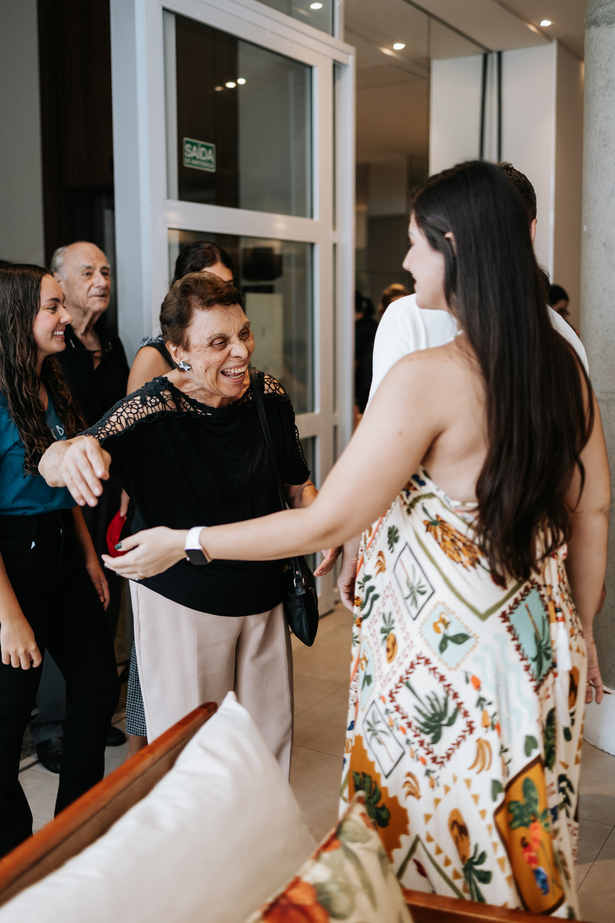 Foto da gestante recebendo convidados com alegria no salão.