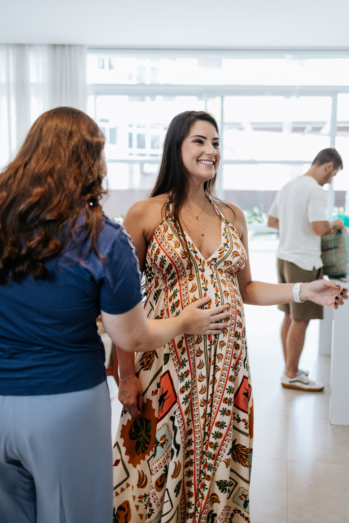 Foto da gestante recebendo carinho na barriga de uma convidada.