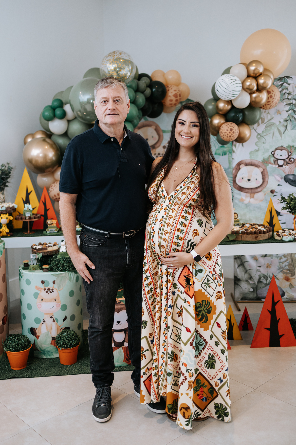 Foto oficial da gestante com um familiar ao lado da mesa do bolo.