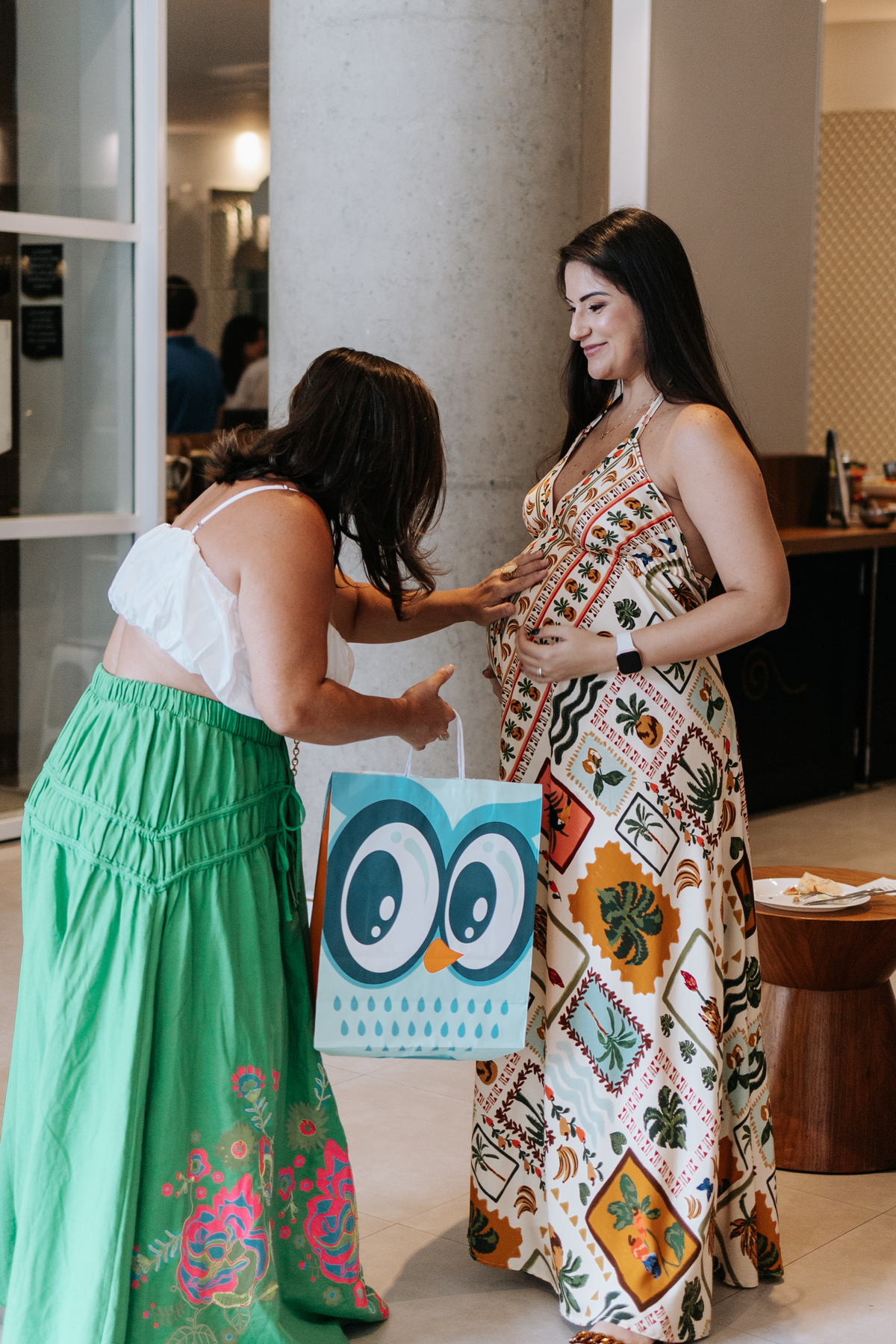 Foto de convidada fazendo carinho na barriga da gestante.